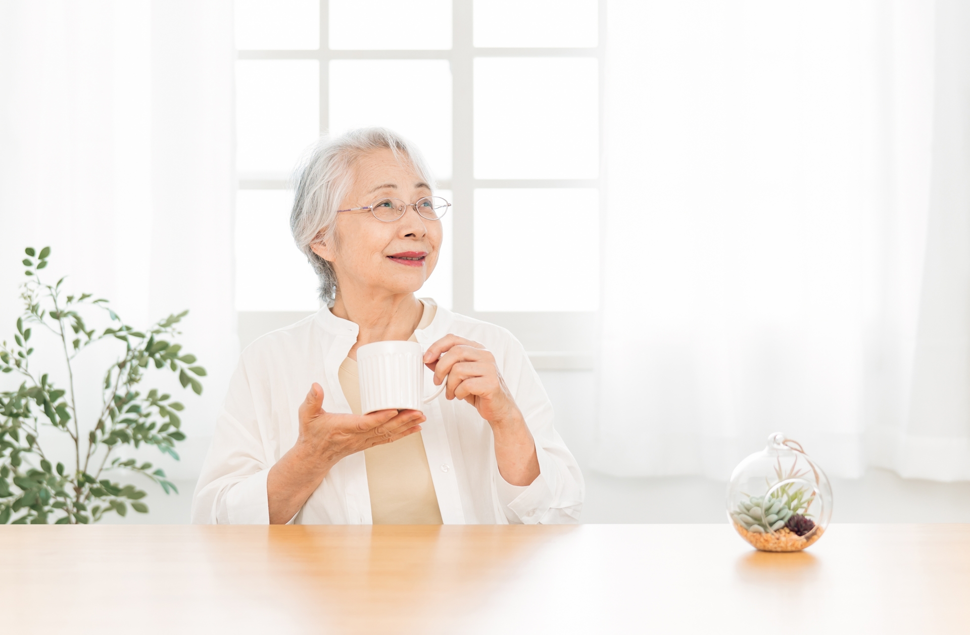 窓辺でお茶を飲みながら穏やかに過ごす女性